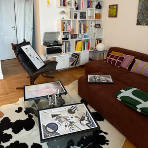 Living room with brown sofa, glass coffee table, and bookshelf.