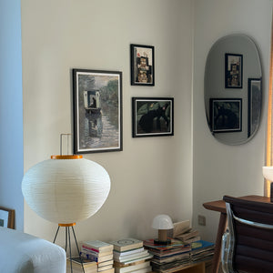 Living room with framed pictures on the wall, books on a table, and a lamp.