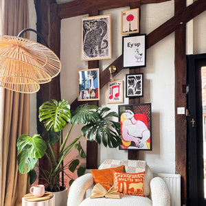 Living room with a white armchair, decorative pillows, plants, and wall art.